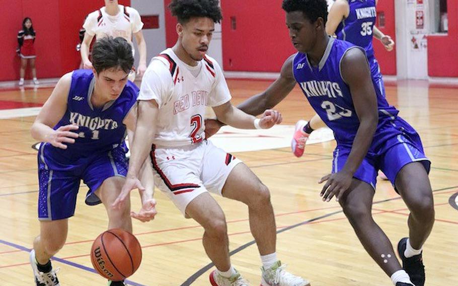 Nile C. Kinnick's James Mincey tries to dribble between Christian Academy Japan defenders during Friday's Kanto Plain boys basketball game. The Knights won 68-64.