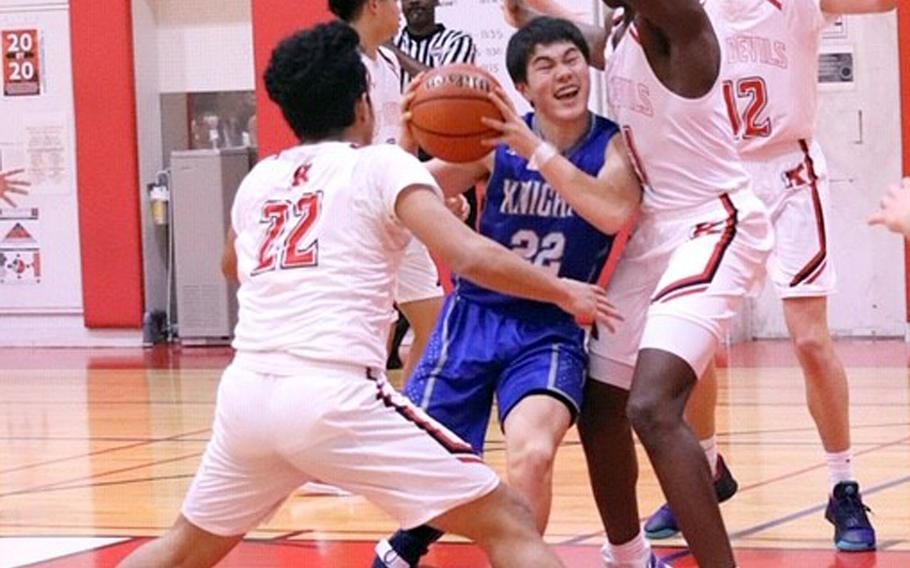 Christian Academy Japan's Koji Matsuoka drives between Nile C. Kinnick defenders during Friday's Kanto Plain boys basketball game. The Knights won 68-64.