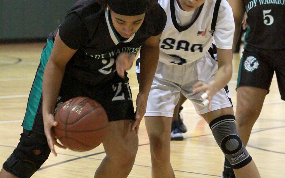 Daegu's Katrina Vasquez picks up the ball next to Osan's Athena Riddick during Saturday's Korea Blue girls basketball game. The Warriors won 62-38 and captured their second straight regular-season title.