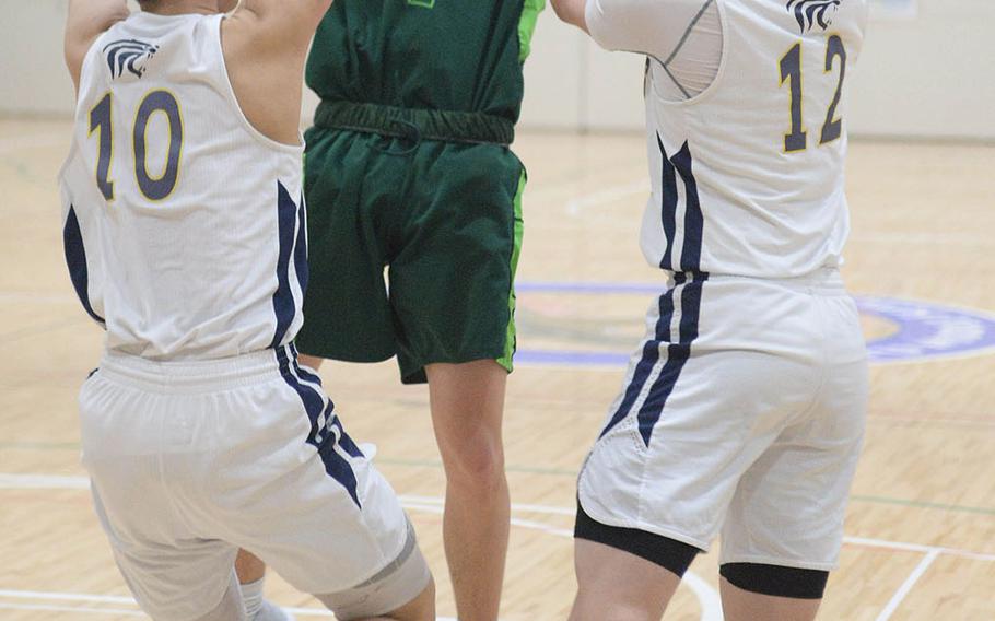 Kubasaki's Mason Taylor finds himself tied up between Taipei American defenders during Saturday's Taipei Basketball Exchange boys game. The Dragons rallied to win 63-58.