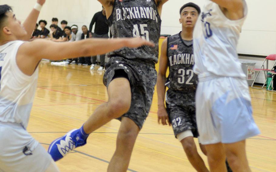 Humphreys' Collin Metcalf tries to shoot between two St. Paul Christian defenders during Thursday's ASIJ Kanto Classic boys game. The Warriors stunned the defending champion Blackhawks 36-35 in the tournament opener.