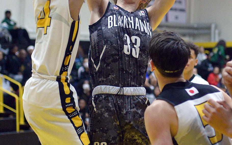 Humphreys' Connor Coyne tries to shoot past the block of Kadena's Kai Harris during Friday's ASIJ Kanto Classic boys game. In what many observers called a possible championship-game preview, the defending champion Blackhawks edged the Panthers 49-46.