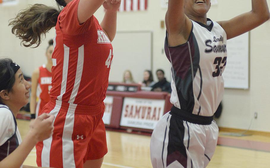 Matthew C. Perry's Vileyni Montero snags a rebound in front of Nile C. Kinnick's Madelyn Gallo during Friday's DODEA-Japan girls basketball game. The Red Devils won 59-6.