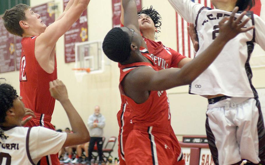 Nile C. Kinnick's Ethan Yuska, Tijari Marshall and Tristan Venturina and Matthew C. Perry's Joseph Andres reach for a rebound during Friday's DODEA-Japan boys basketball game. The Red Devils won 62-39.