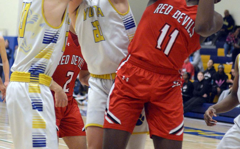 Nile C. Kinnick's Tijari Marshall pulls a rebound away from Yokota's Connor Rowan and Mickey Galvin during Friday's DODEA-Japan boys semifinal, won by the Red Devils 68-64.