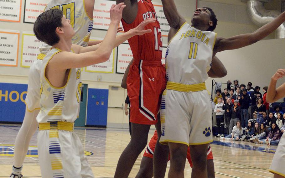 Nile C. Kinnick's Corey Hollingsworth snags a rebound over Yokota's Marcus Berrette, Connor Rowan and Mickey Galvin during Friday's DODEA-Japan boys semifinal, won by the Red Devils 68-64.