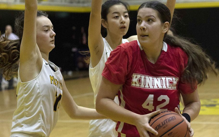 Nile C. Kinnick's Madelyn Gallo drives against two American School In Japan defenders during Tuesday's Kanto Plain girls basketball game. The Mustangs won 36-20.
