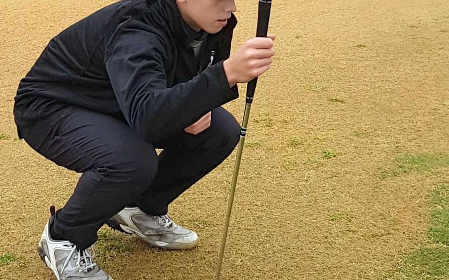 Humphreys Black's Cade White studies the greeen before a putt from the fringe during Thursday's DODEA-Korea golf. White lost to Humphreys Gold's Ethan Elliott 5-up.