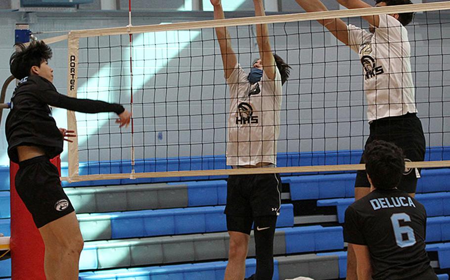 Osan's Timothy Petrae spikes through a Humphreys Gold double block of Austin Mills, center, and Collin Metcalf during Friday's DODEA-Korea district boys volleyball final. Gold won in three sets.
