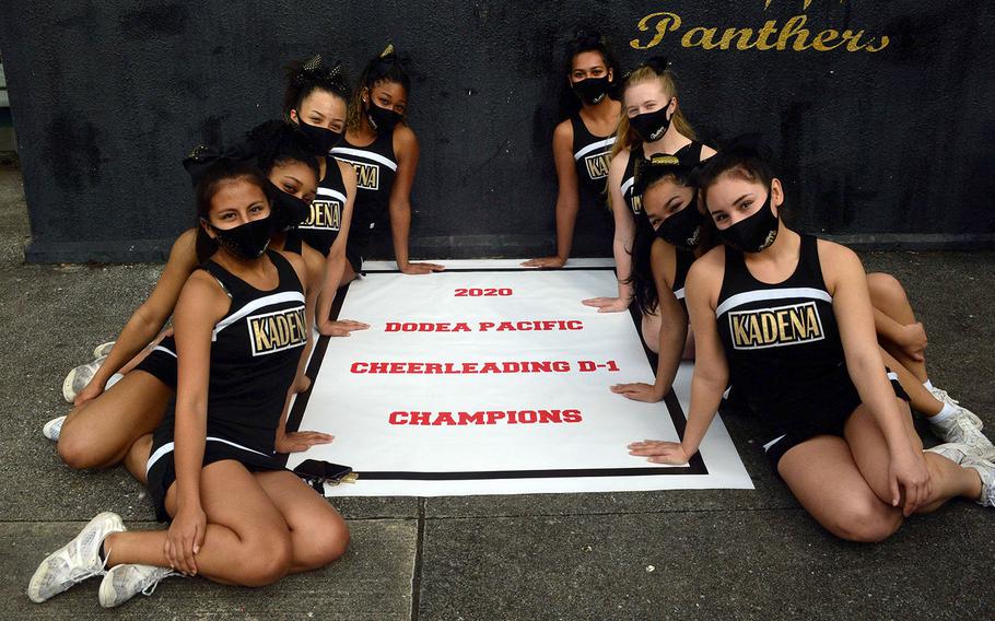 Kadena's cheerleaders gather 'round the Far East Division I team title banner.