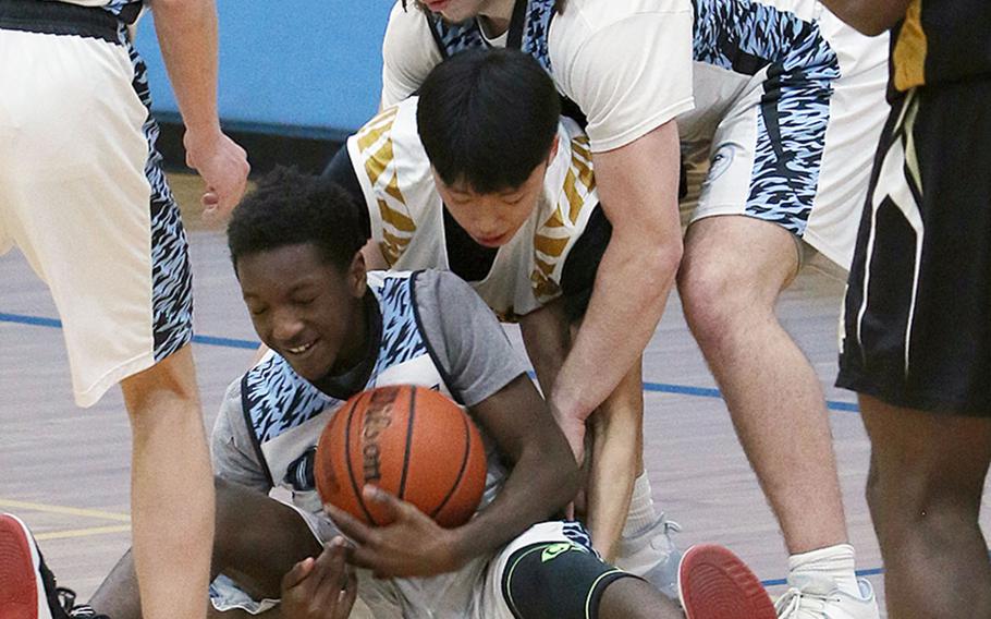 Osan's Adrian Perry ties up the ball against Humphreys Black during Wednesday's Korea boys basketball game. The Blackhawks won 77-64.
