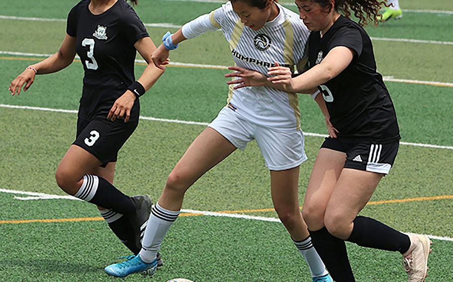Humphreys' Arielle Stickar plays the ball between Daegu's Leah Williamson and Lisa Lyons during Saturday's DODEA-Korea girls soccer championship match. The Blackhawks won 2-0.