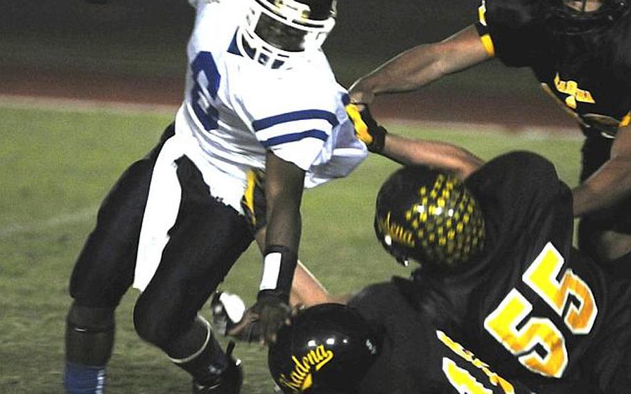 Seoul American running back Demetrius Johnson tries to avoid the tackle of Kadena defenders Rodney Goodson (10), Tyler Broome (55) and Sean O'Neil during last year’s DODEA Pacific Far East High School Class AA football championship game in Okinawa. Until this season, the only time Korea and Okinawa schools got together to play football was in the playoffs. Now, the teams play a full schedule of DODDS-funded games against each other.