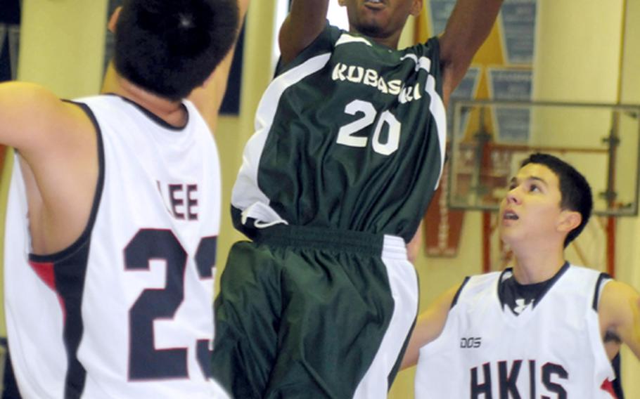 Kubasaki guard Ryan Jackson (20) shoots between host Hong Kong International defenders Lawrence Lee (23) and Kevin Matthews (4) during Thursday's pool-play game in the 41st Hong Kong International School Holiday Basketball Tournament. Kubasaki held off Hong Kong 74-70.