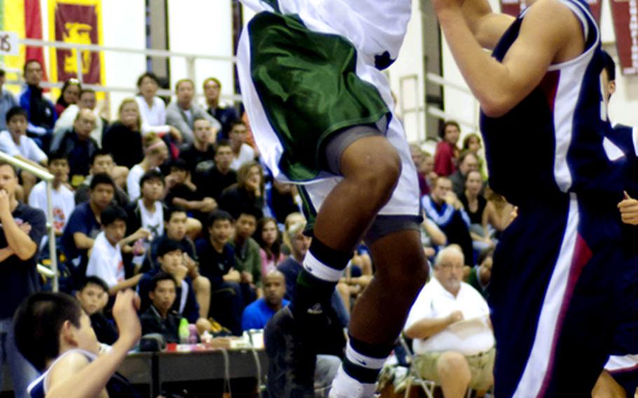 Kubasaki forward A.J. Watson (15) puts up a shot and plows into Hong Kong International's Jeff Chow (9) as Hong Kong's Adam Xu watches during Saturday's boys championship game.