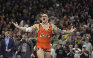 A wrestler walks in front of a crowd of people during an event.