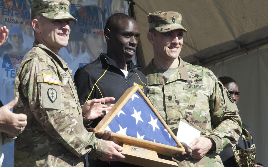 Spc. Paul Chelimo poses with a flag that was flown over the Pentagon after the Army Ten-Miler outside the Pentagon on Oct. 11, 2015. Chelimo won the race with a time of 48:19.