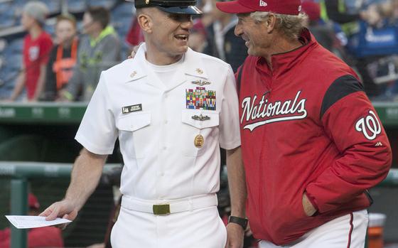 Master Chief Petty Officer of the Navy Steven Giordano is joined by Washington Nationals bench coach Chris Speier as he walks out to deliver the lneup card to the umpires on U.S. Navy Day at Nationals Park in Washington, D.C., May 3, 2017.