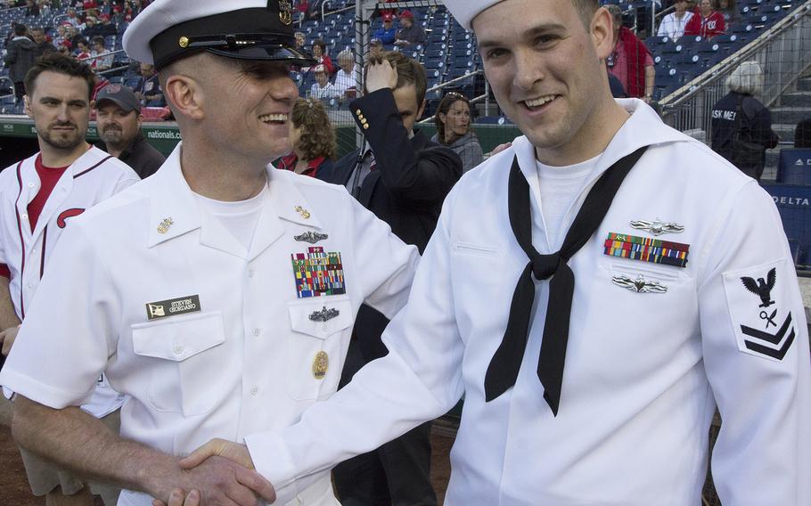 Master Chief Petty Officer of the Navy Steven Giordano congratuates Intelligence Specialist 2nd Class Sean Grimes, Secretary of the Navy sailor of the year, after Grimes threw out the ceremonial first pitch on U.S. Navy Day at Nationals Park in Washington, D.C., May 3, 2017.