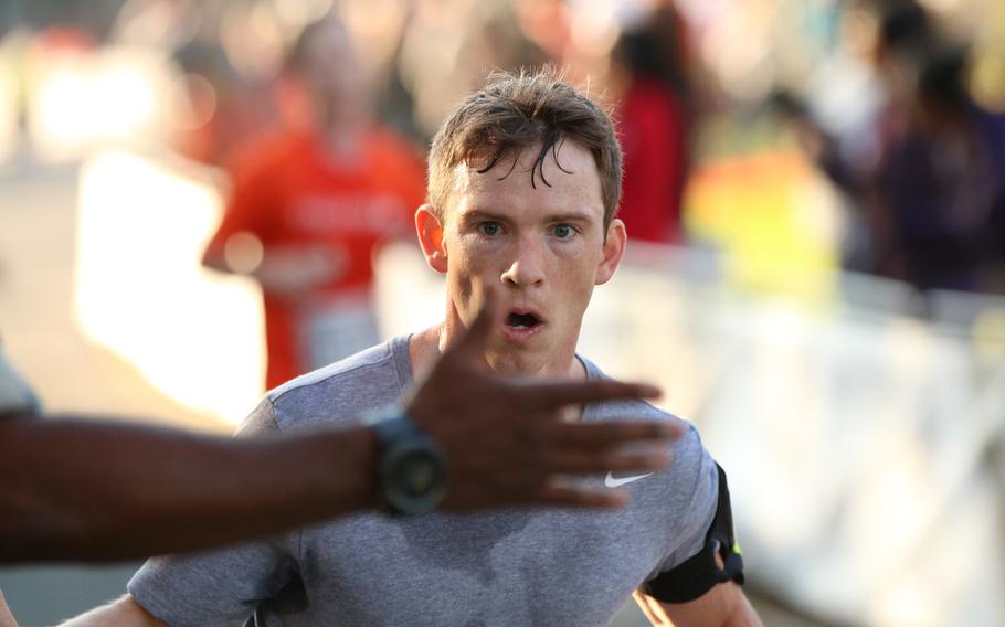 A runner eyes an incoming high-five as he crosses the finish line of the 10k run event held in conjunction with the 42nd Marine Corps Marathon on Oct. 22, 2017.