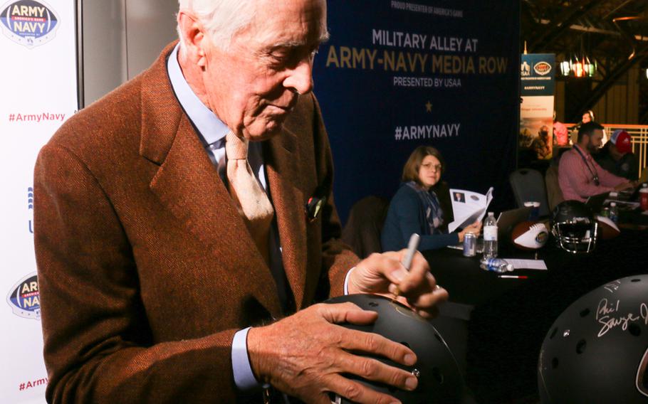 West Point graduate, Heisman Trophy winner and former Army infantry officer Pete Dawkins signs a helmet at the pre-game media event held in Philadelphia ahead of the 2017 Army-Navy game. 