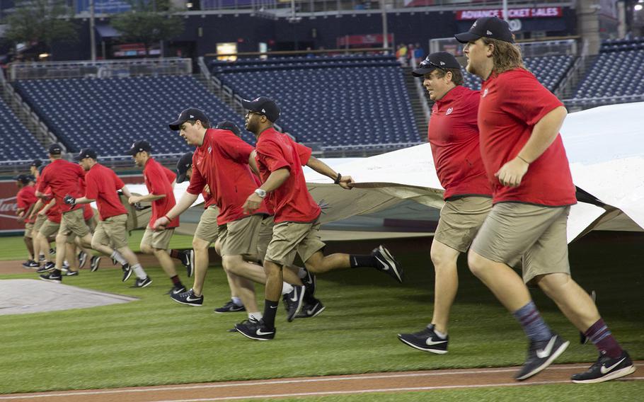The Washington Nationals' grounds crew clears the tarpaulin after a pre-game downpour on May 22, 2018.