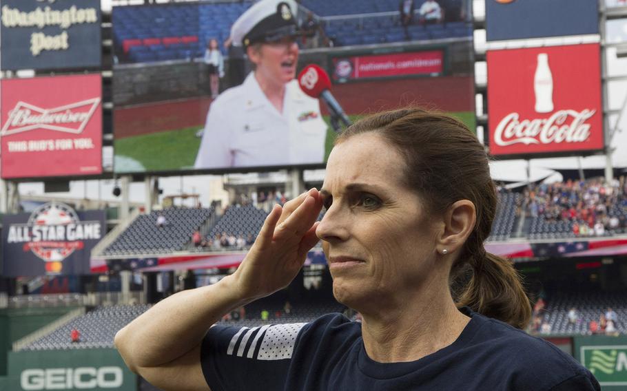 Rep. Martha McSally, R-Ariz., salutes as the national anthem is sung by Chief Musician Shana Sullivan of the U.S. Navy Band (shown on the scoreboard) before a game on May 22, 2018. McSally, a former U.S. Air Force combat pilot, threw out the ceremonial first pitch to mark Women in the Military Day at Nationals Park.