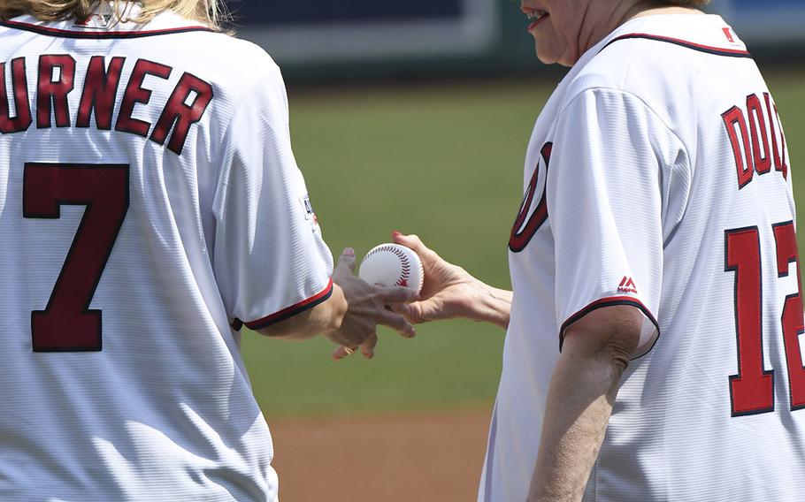 Former Sen. Elizabeth Dole hands a baseball to military caregiver Megan Smith for the ceremonial first pitch before a game between the Washington Nationals and Boston Red Sox in Washington, D.C., July 4, 2018.
