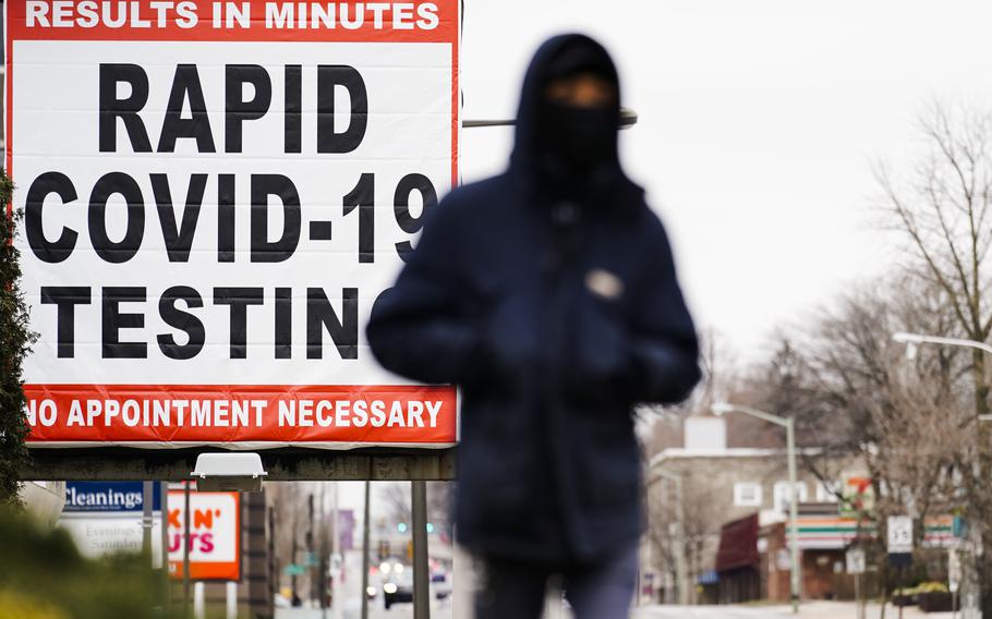 A person wearing face mask walks near a sign advertising a rapid COVID-19 testing site in Philadelphia on Jan. 25, 2021. U.S. healthy officials say that most fully vaccinated Americans can skip testing for COVID-19, even if they were exposed to someone infected.  