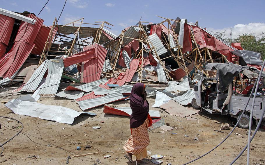 A Somali woman watch the destruction after car bomb attack on a European Union military convoy in the capital Mogadishu, Somalia Monday, Sept. 30, 2019. A Somali police officer says a suicide car bomber has targeted a European Union military convoy carrying Italian military trainers in the Somali capital Monday.