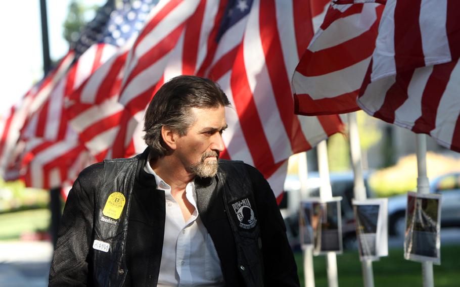 David Keyes reads the stories of Idaho's fallen soldiers, which were posted on flagpoles at the Idaho Fallen Soldier memorial service at the Idaho Fallen Soldier Memorial in downtown Boise, Idaho, Tuesday, September 11 2012.  