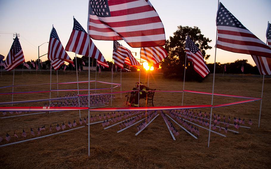 American flags surround a firefighter figure at the September 11 Memorial in West Sacramento, Calif., as the sun sets, September 10, 2012. 