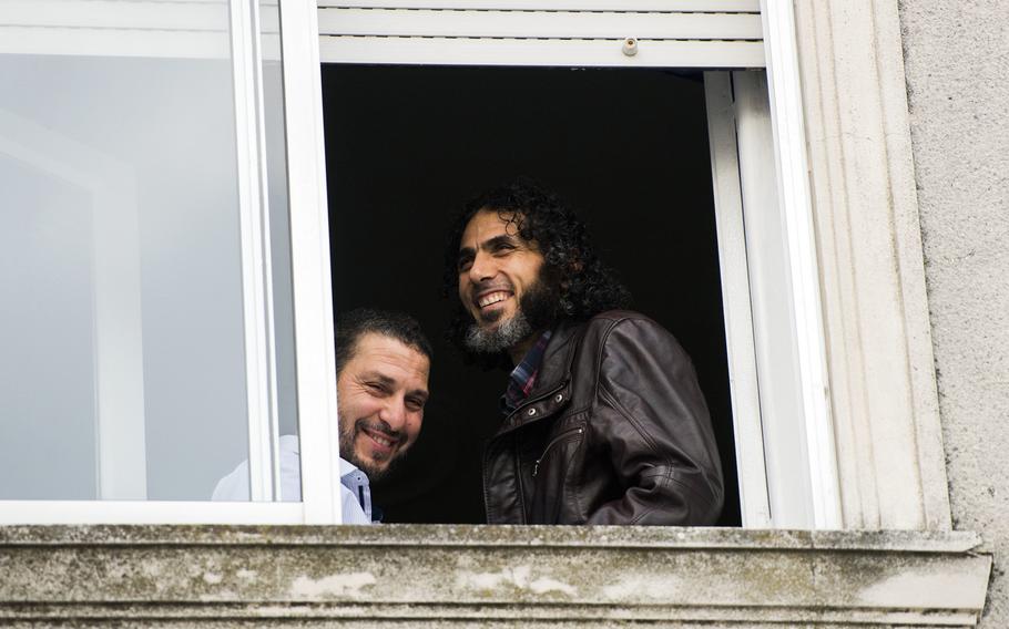 Adel bin Muhammad El Ouerghi, left, of Tunisia, and Abu Wa'el Dhiab, from Syria, both freed Guantanamo Bay detainees, look out a window of their home in Montevideo, Uruguay, in June 2015. A Brazilian airline is asking its employees to be on the lookout for Dhiab, who was supposed to have traveled to Brazil, but Brazil said there is no record of his entering the country.