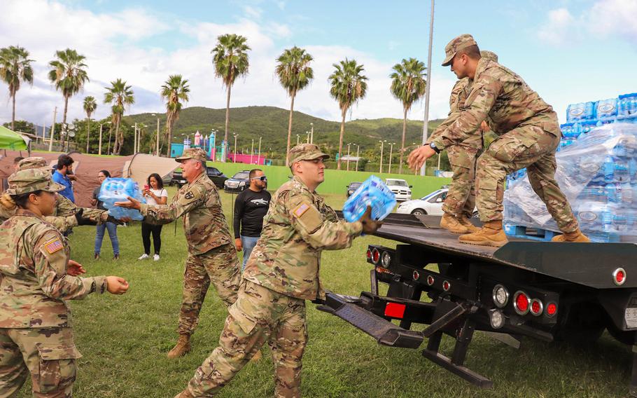 Members of the Puerto Rico National Guard's 105th Quartermaster Company of the 3678th Combat Sustainment Support Battalion move cases of bottled water for people staying at a shelter at the Mariano Rodriguez Coliseum in the Municipality of Guayanilla, following a 6.4-magnitude earthquake that shook the southern half of the island Tuesday.
