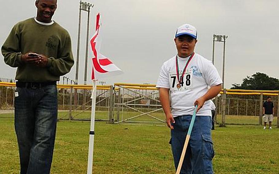 Lance Cpl. Kashay Patterson from Myrtle Beach, S.C., watches as a Special Olympics athlete putts the ball toward the pin in the ground golf event at the 2010 Kadena Special Olympics on Saturday.