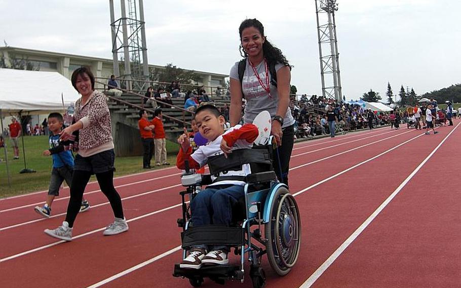 Ten-year-old Keita Chinen, center, is escorted by Marine Staff Sgt. Ramarie Moore of Camp Foster at the Kadena Special Olympics on Saturday at Kadena Air Base. About 800 special needs athletes and more than 3,000 American and Japanese volunteers participated in the annual event, which began in 2000 to strengthen ties between the U.S. and Okinawan communities on the island.