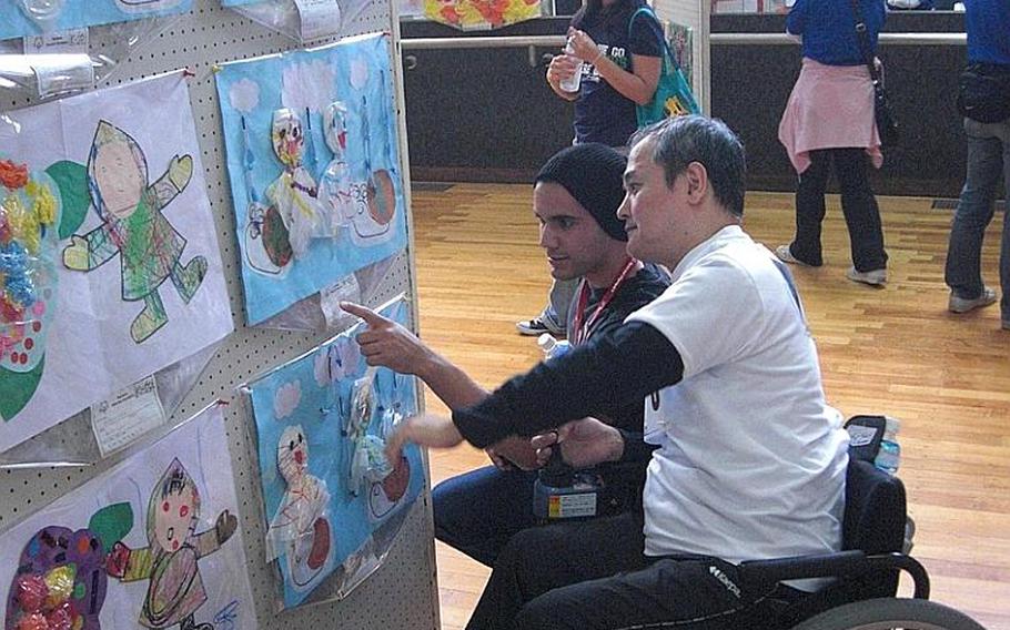 Petty Officer Jason Valdovinos, 21, of Marine Corps Air Station Futenma, and Jun Okawa, 48, of Okinawa City, view the exhibit created by 700 special needs artists at the Risner Gym on Saturday. The Kadena Special Olympics drew more than 5,000 people from military and Okinawan communities, including about 800 special needs athletes and more than 3,000 American and Japanese volunteers as well as senior officials from both communities.