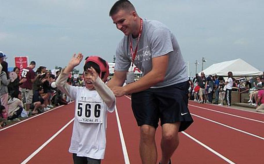 Yudai Miyagi, 8, of Okinawa City, starts celebrating his accomplishment in the 30-meter race during the 2010 Kadena Special Olympics on Saturday at Kadena Air Base. His escort, Marine Cpl. Mike Teany, 20, from Camp Foster, said his young Okinawan friend is too energetic to catch up with.