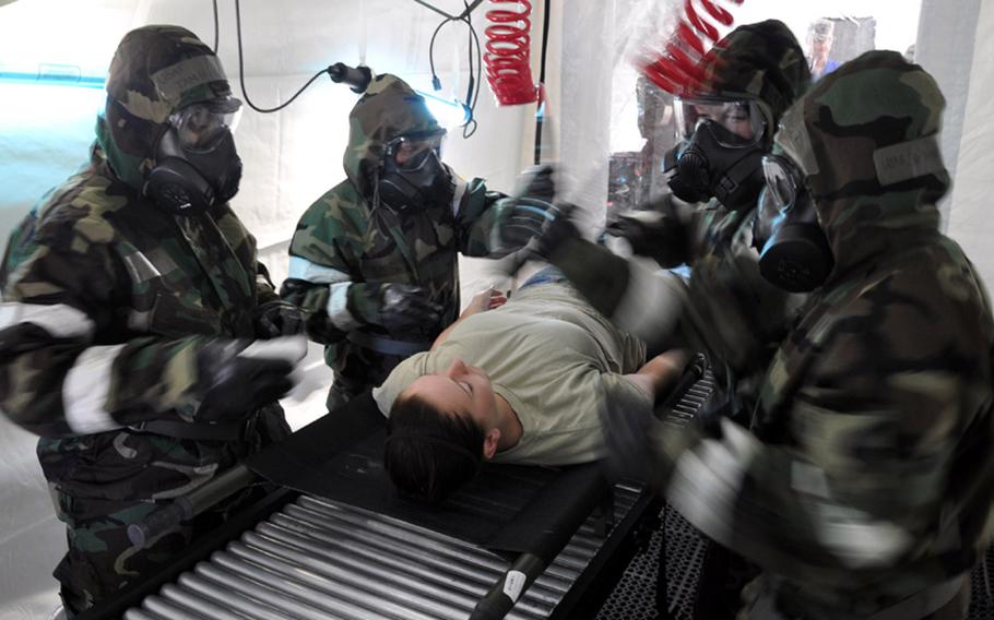Base medical personnel run the 'victim' of a simulated attack through a decontamination tent Tuesday at Misawa Air Base, Japan. 