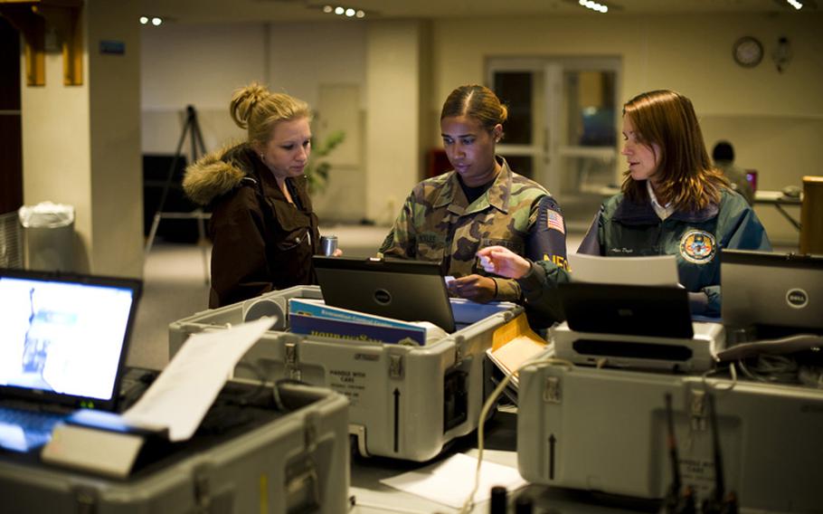 From left, Andrea Slayton, Staff Sgt. Trisha Mickles and Alica Doyle, Non-combatant Evacuation Operations Tracking System administrators, process simulated incoming evacuees in the Mokuteki Community Center during an operational readiness exercise at Misawa Air Base, Japan on Nov. 4. The system allows bases to keep track of evacuees and make sure they arrive at their destination.
