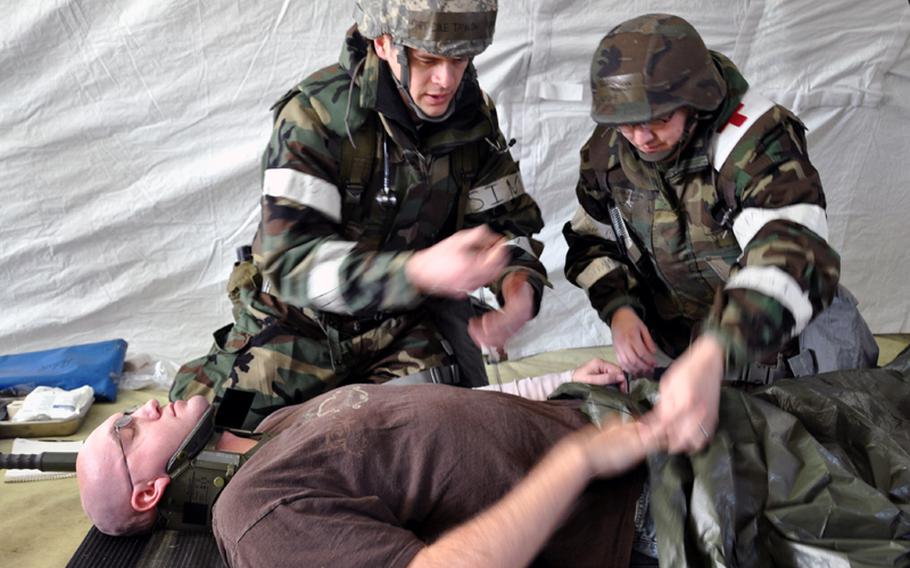 Capt. Cole Taylor, left, and Senior Airman Robert Quinn treat Senior Airman Donald Alsept as a 'victim' of a simulated attack during a training exercise Tuesday at Misawa Air Base, Japan.