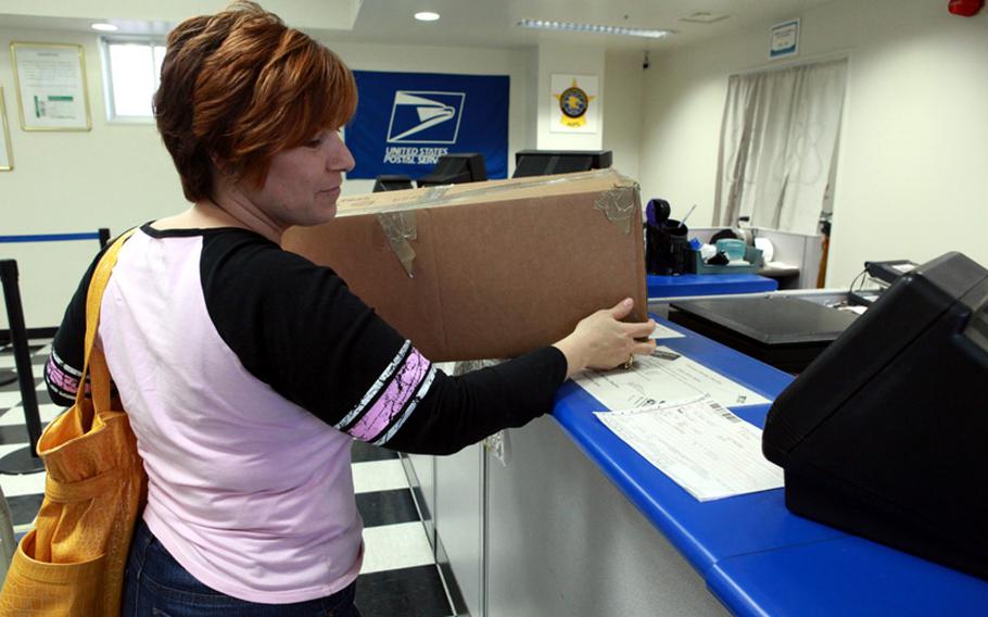 Judy Theroit, a military dependent at Yokota Air Base, Japan, sends a package to her deployed husband from Yokota's post office. Postal officials are encouraging customers to get their holiday packages in the mail as early as possible.