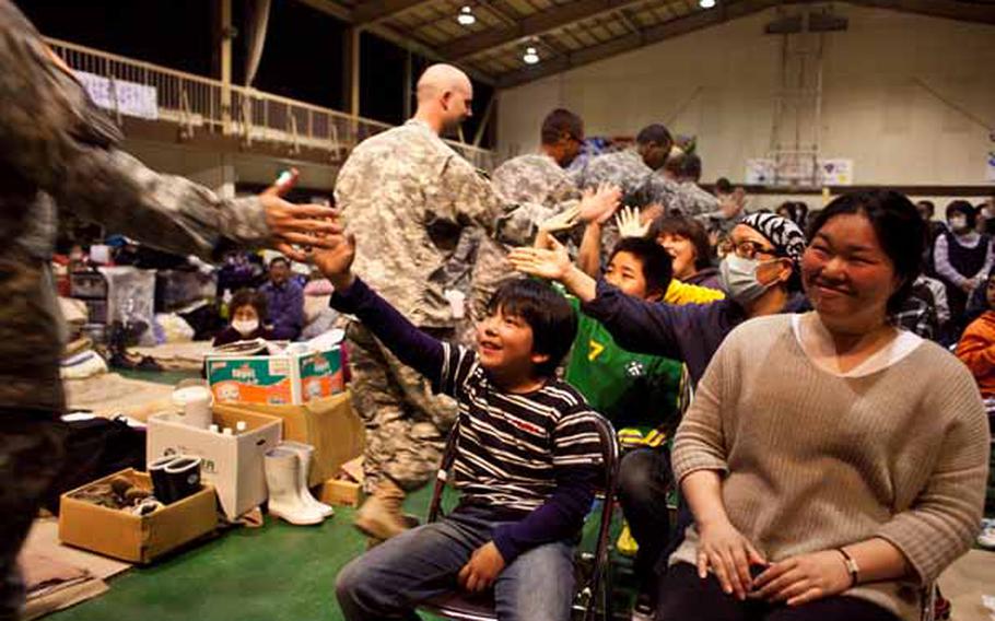 Members of the Camp Zama Army Band share "high fives" with children at the Rokugo Middle School shelter in Sendai City, Japan, prior to playing a concert for the displaced residents.