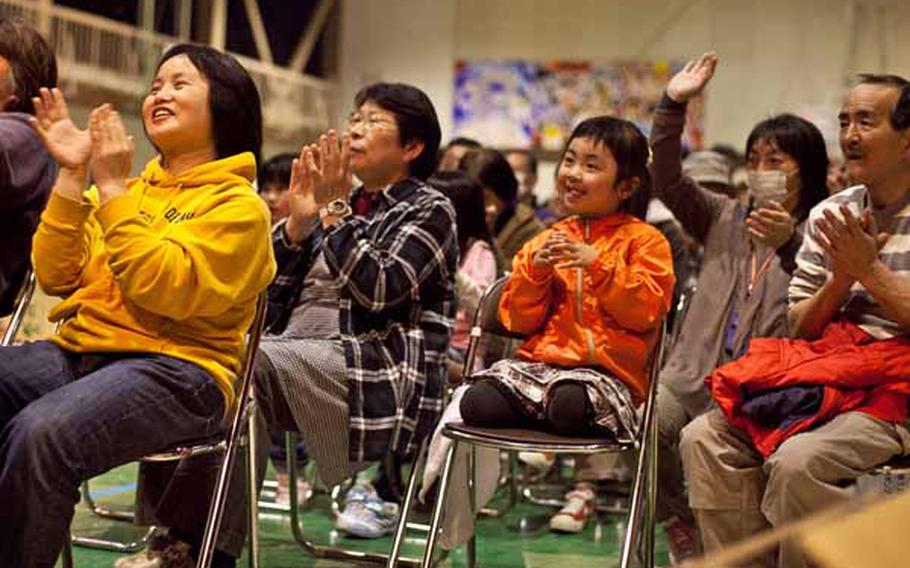 Displaced residents at the Rokugo Middle School shelter in Sendai City, Japan, clap along to the music during a concert by the Camp Zama Army Band.