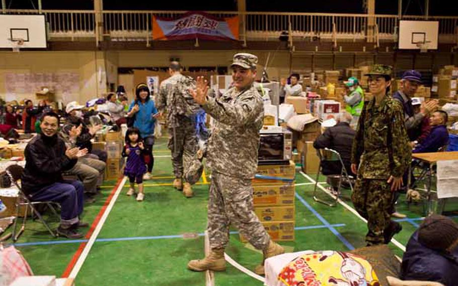 Spc. Eddie Sneed, 28, a saxaphone player for the Camp Zama Army Band, along with 14 other members leaves Rokugo Middle School shelter in Sendai City to a round of applause after playing a concert to the displaced residents there.