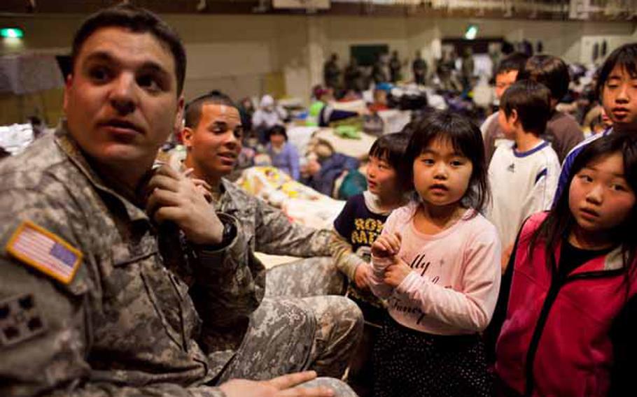 Spc. Eddie Sneed, 28, a saxaphone player for the Camp Zama Army Band, asks for a gift for a girl at the Rokugo Middle School shelter in Sendai City. The band played a concert for the residents and brought gifts for the children donated by the Camp Zama Boy Scouts and Girl Scouts associations.