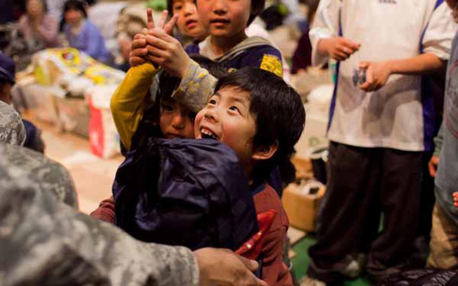 A boy at the Rokugo Middle School shelter in Sendai City, Japan receives a gift donated by the Boy Scout and Girl Scout associations of Camp Zama, after a concert by the Camp Zama Army Band.