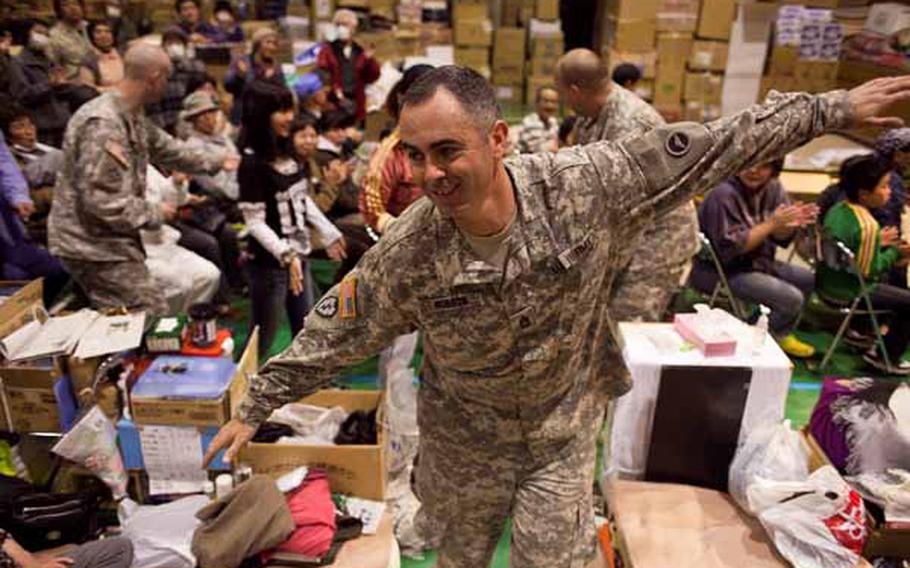Sgt. 1st Class Bill Hobson, 31, a member of the Camp Zama Army Band leads a conga line of soldiers and displaced residents around the Rokugo Middle School shelter in Sendai City, Japan during a concert they played for the residents. 