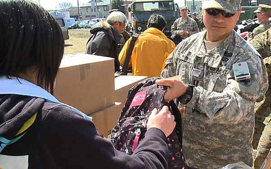 Capt. Jesse Iglesias, from U.S. Army Japan’s Logistics Task Force 35, hands a backpack to a  child in Miyagi prefecture as part of “Operation Backpacks.”  Backpacks full of toys, clothes, blankets, and hygiene items have been handed out to the displaced children in northern Japan following the devastating March 11 earthquake and tsunami hit the region.