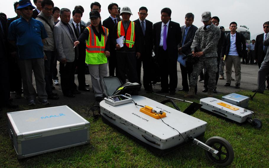 Sarah Woo, chief of the environmental section of the U.S. Army Corps of Engineers Far East District, shows reporters and local officials Thursday the ground-penetrating radar that will be used at Camp Carroll, South Korea. The radar will be used to search for barrels of Agent Orange allegedly buried at the camp. The radar can locate objects underground and determine change in soil density that could indicate where previous digging occurred. 